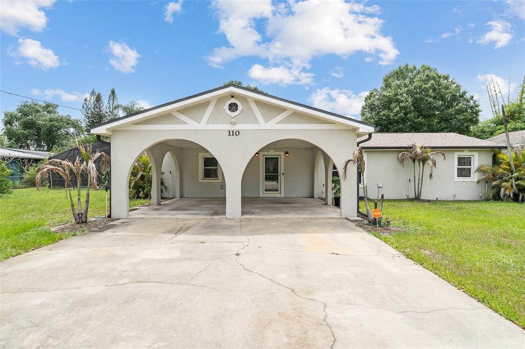 A single-story house with a double-arched carport and a concrete driveway under a cloudy sky — 110 EDGEWATER DR, ST CLOUD, FL