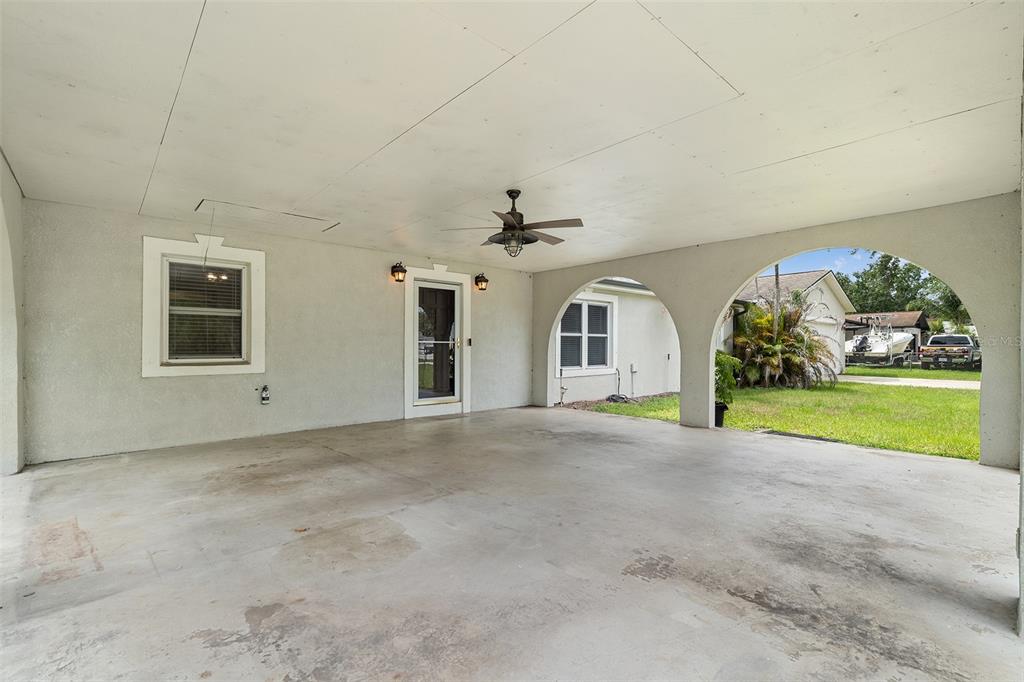A covered concrete patio features arched openings, a ceiling fan, and a glass-paneled door — 110 EDGEWATER DR, ST CLOUD, FL