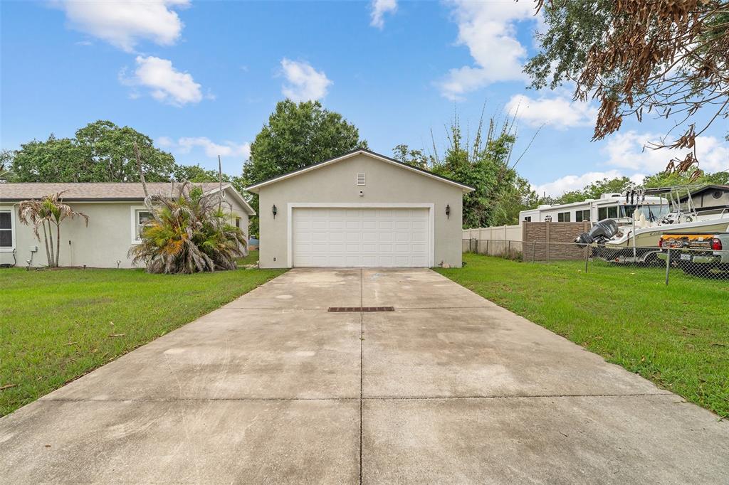 A concrete driveway leads to a detached two-car garage next to a residential home — 110 EDGEWATER DR, ST CLOUD, FL