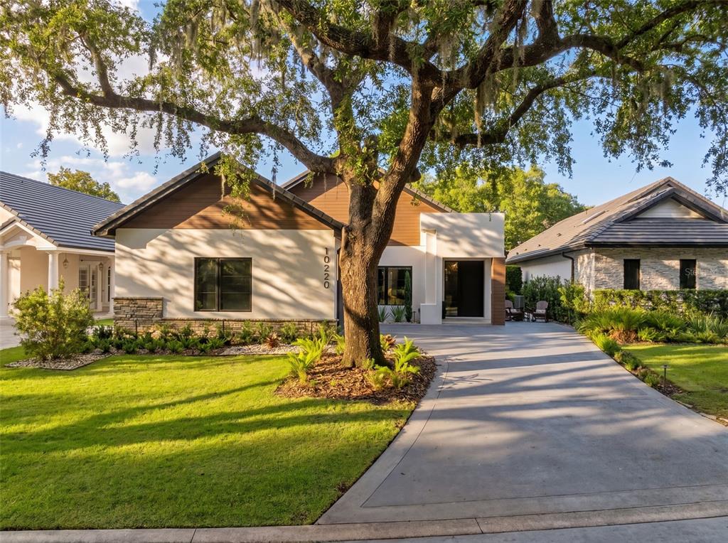 A modern single-story house with a large oak tree in the front yard — 10220 CHILTERN GARDEN DRIVE, ORLANDO, FL