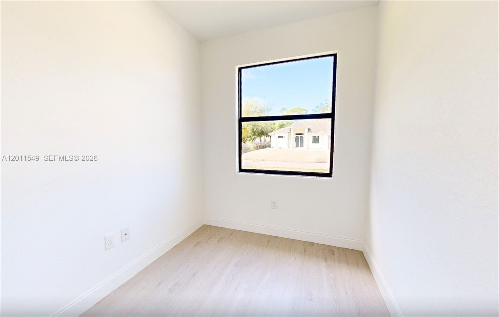 An empty room with white walls, light wood-look flooring, and a single window — 618 SHELDON AVE, Lehigh Acres FL 33936, LEHIGH ACRES, FL