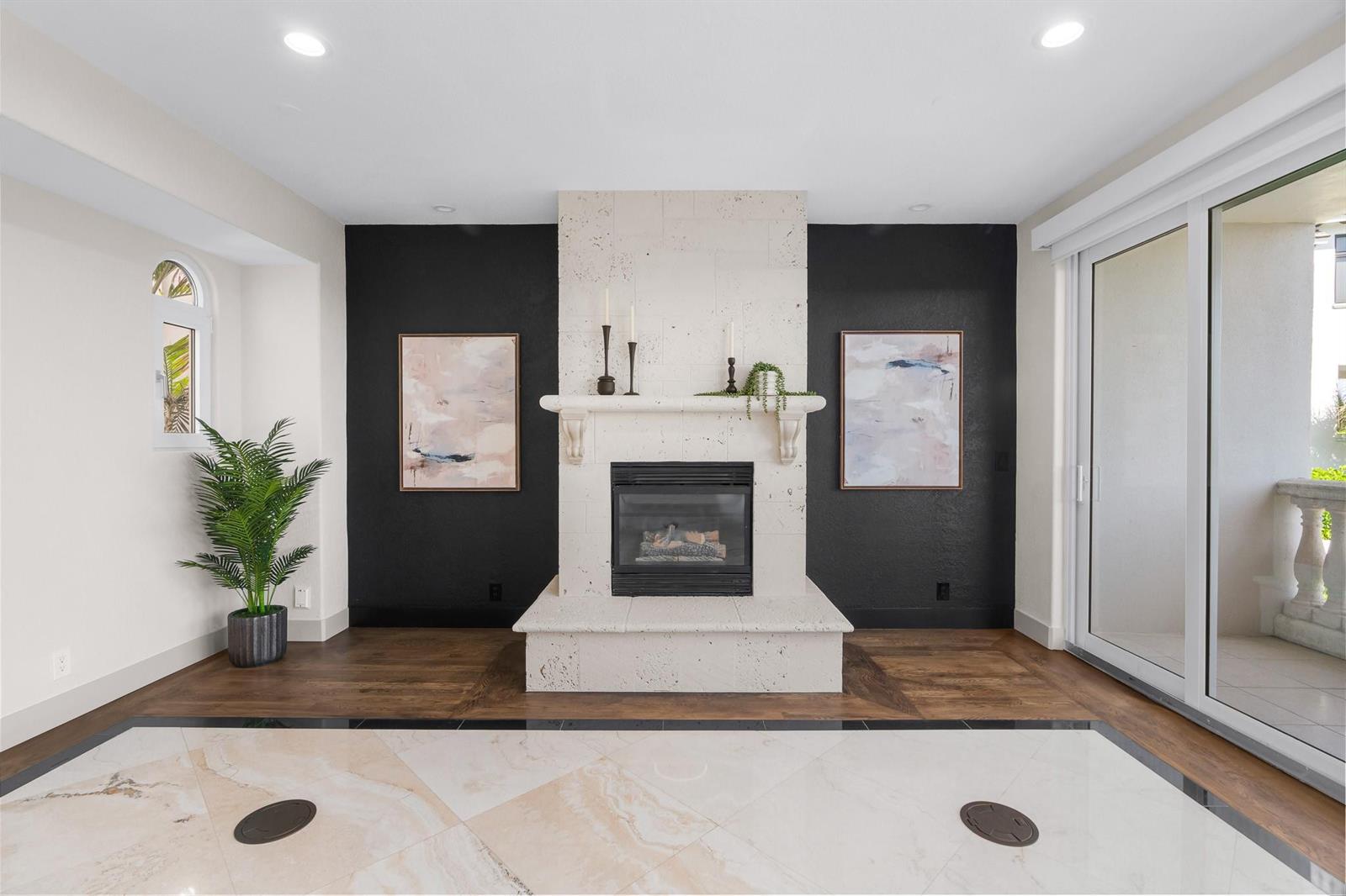 A living room features a stone fireplace between two black walls and light marble flooring — 1796 Bay Drive # 1796, Pompano Beach FL 33062, POMPANO BEACH, FL