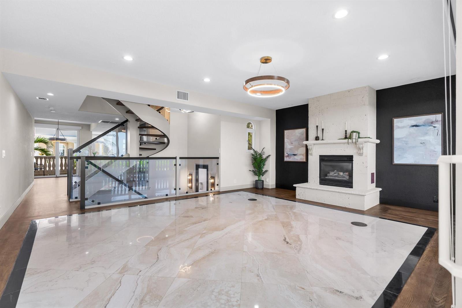 A spacious living room features a spiral staircase, a fireplace, and large marble floor tiles — 1796 Bay Drive # 1796, Pompano Beach FL 33062, POMPANO BEACH, FL