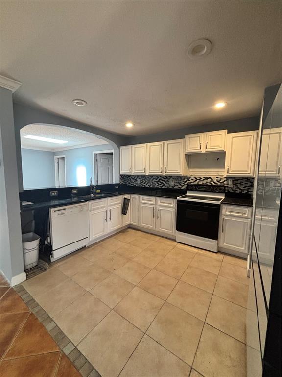 A kitchen with white cabinets, black countertops, a tiled floor, and a pass-through window — 2487 HARBOUR WAY, WINTER PARK, FL