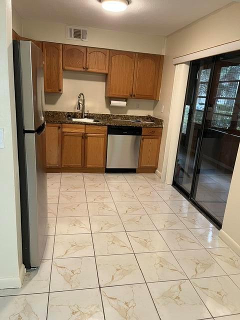 A kitchen features wood cabinets, granite countertops, stainless steel appliances, and light-colored tiled flooring — 207 Capri E # 207, Delray Beach FL 33484, DELRAY BEACH, FL