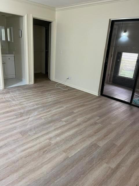 An empty room features light wood-look flooring, a sliding glass door, and an adjacent bathroom — 207 Capri E # 207, Delray Beach FL 33484, DELRAY BEACH, FL