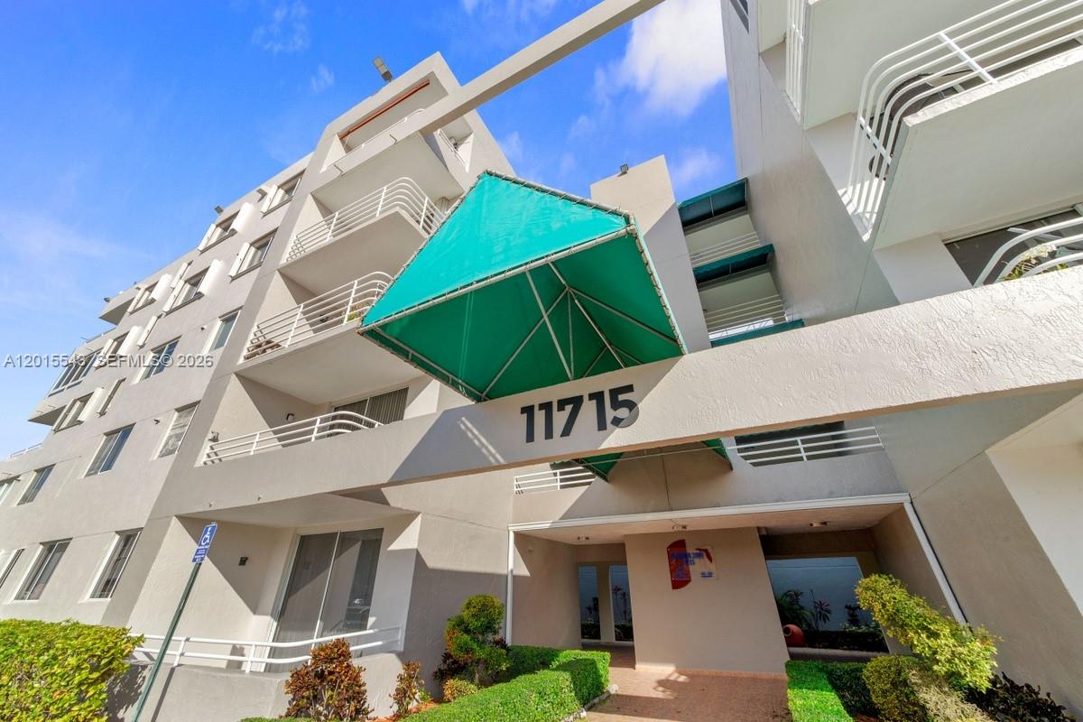 A low-angle view shows the exterior of a multi-story apartment building with a green awning — 11715 SW 18th St # 410, Miami FL 33175, MIAMI, FL