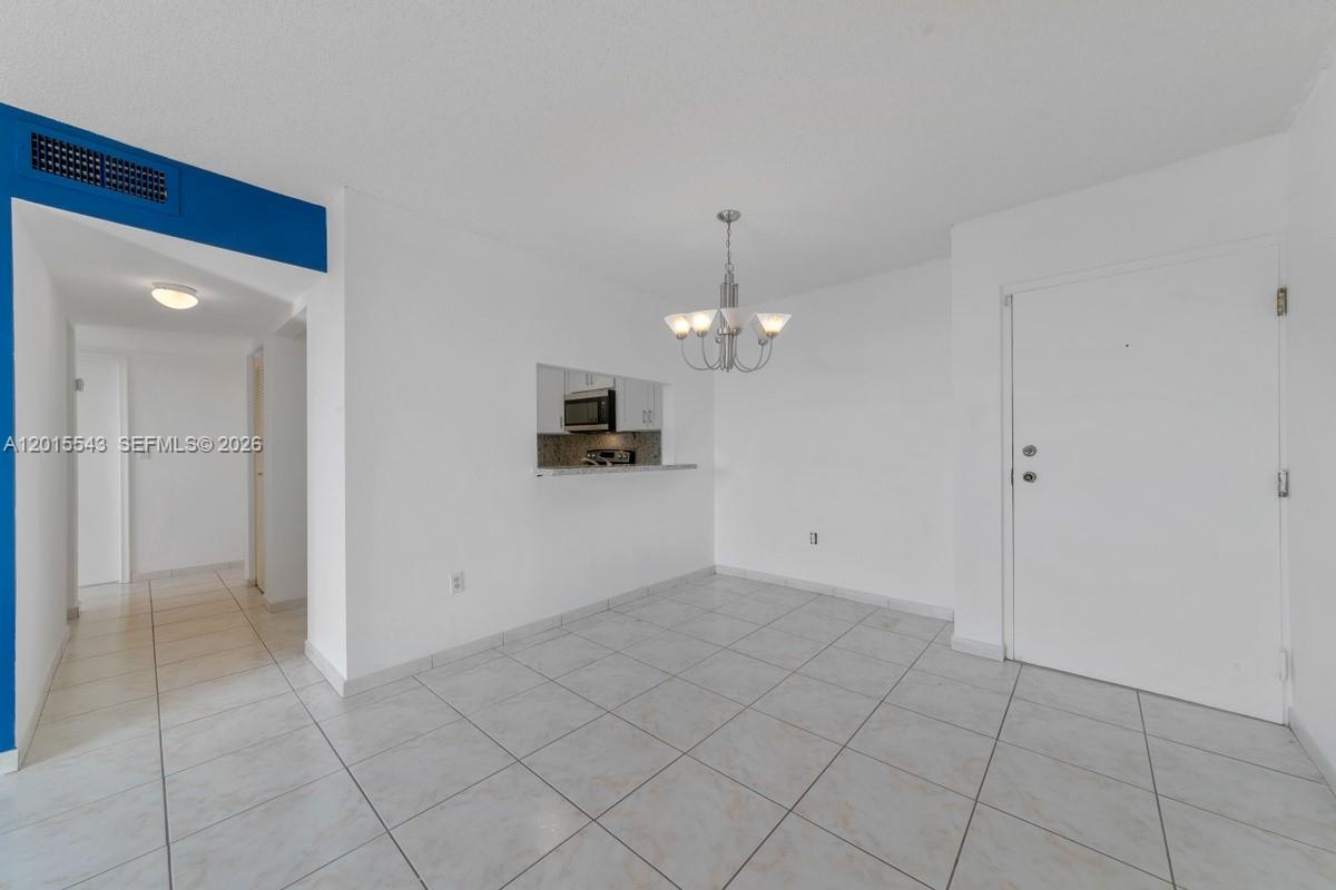 This dining area features white tile flooring, a chandelier, and a pass-through to the kitchen — 11715 SW 18th St # 410, Miami FL 33175, MIAMI, FL