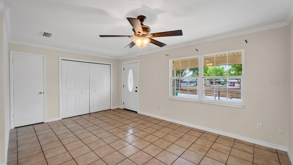 A room with beige walls, tile flooring, a ceiling fan, and a white entry door — 2791 FULFORD STREET, DELTONA, FL