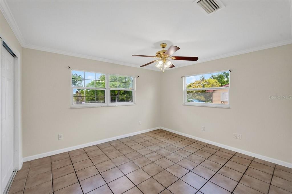 An empty room with beige walls, tile flooring, a ceiling fan, and two windows — 2791 FULFORD STREET, DELTONA, FL