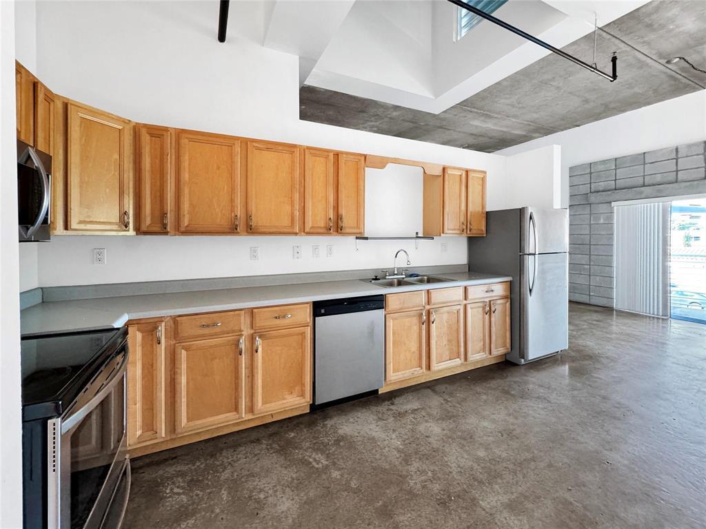 A kitchen features light wood cabinets, stainless steel appliances, and a concrete floor and ceiling — 200 E Dania Beach Boulevard # 208, Dania Beach FL 33004, DANIA BEACH, FL