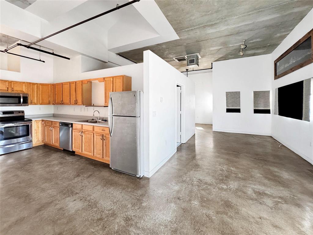 An open-concept kitchen and living area features concrete floors, exposed ceilings, and light wood cabinetry — 200 E Dania Beach Boulevard # 208, Dania Beach FL 33004, DANIA BEACH, FL