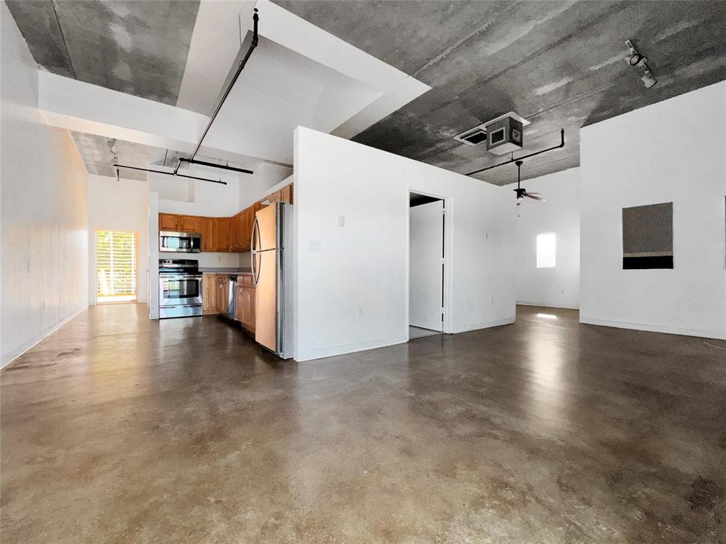 An open-concept loft with concrete floors, exposed ceiling pipes, and a kitchen with wood cabinets — 200 E Dania Beach Boulevard # 208, Dania Beach FL 33004, DANIA BEACH, FL