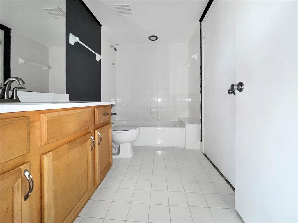 A bathroom features a wooden vanity, white tiled floor, and a white bathtub-shower combination — 200 E Dania Beach Boulevard # 208, Dania Beach FL 33004, DANIA BEACH, FL