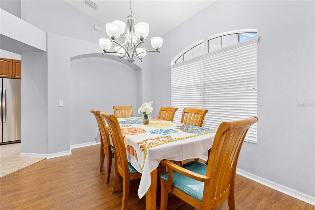 A dining room features a wooden table with a seashell tablecloth, chairs, and a chandelier — 3540 MOONDANCE CIRCLE, BROOKSVILLE, FL