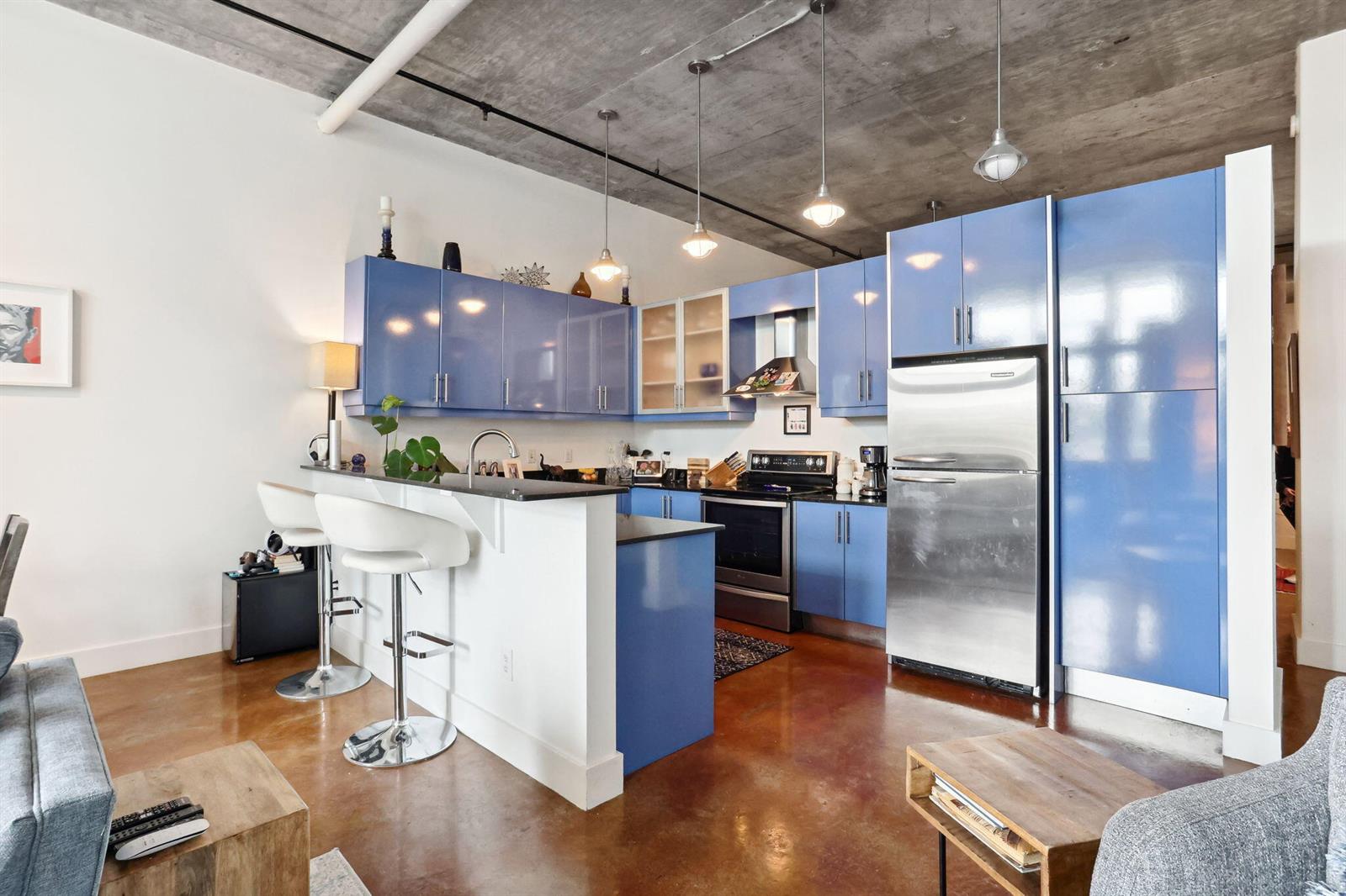 A kitchen with blue cabinets, stainless steel appliances, and a breakfast bar on concrete floors — 180 NE 4th Avenue # 307, Delray Beach FL 33483, DELRAY BEACH, FL