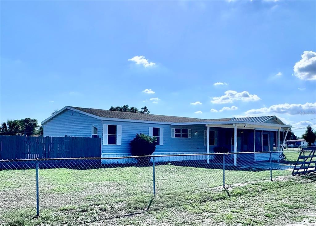 A light blue manufactured home with a covered porch and a chain-link fence — 4300 MEADOW RIDGE AVENUE, MULBERRY, FL
