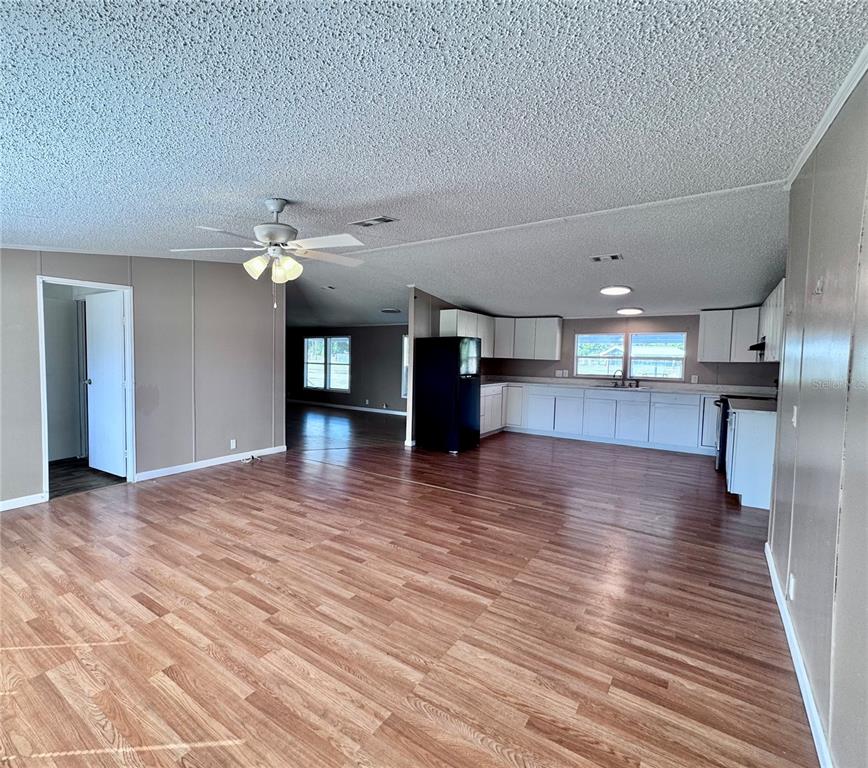 An open-concept living area features wood-look flooring, a ceiling fan, and a kitchen with white cabinets — 4300 MEADOW RIDGE AVENUE, MULBERRY, FL