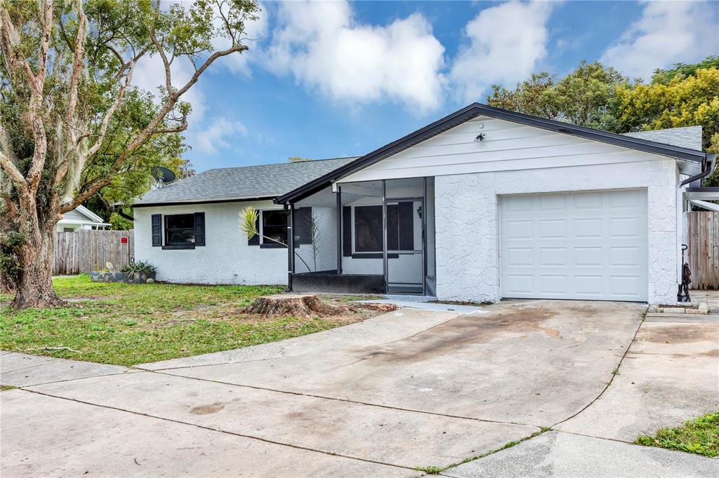 A single-story house with a white stucco exterior, a screened-in porch, and a concrete driveway — 7900 TOLEDO STREET, ORLANDO, FL