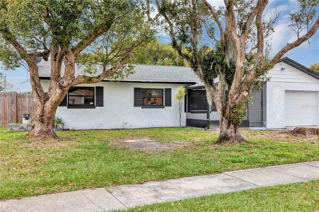 A white single-story house with black shutters, a garage, and two large trees in front — 7900 TOLEDO STREET, ORLANDO, FL