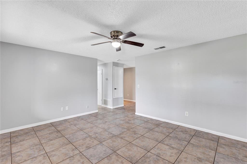 An empty room with gray walls, tiled flooring, and a ceiling fan — 7900 TOLEDO STREET, ORLANDO, FL