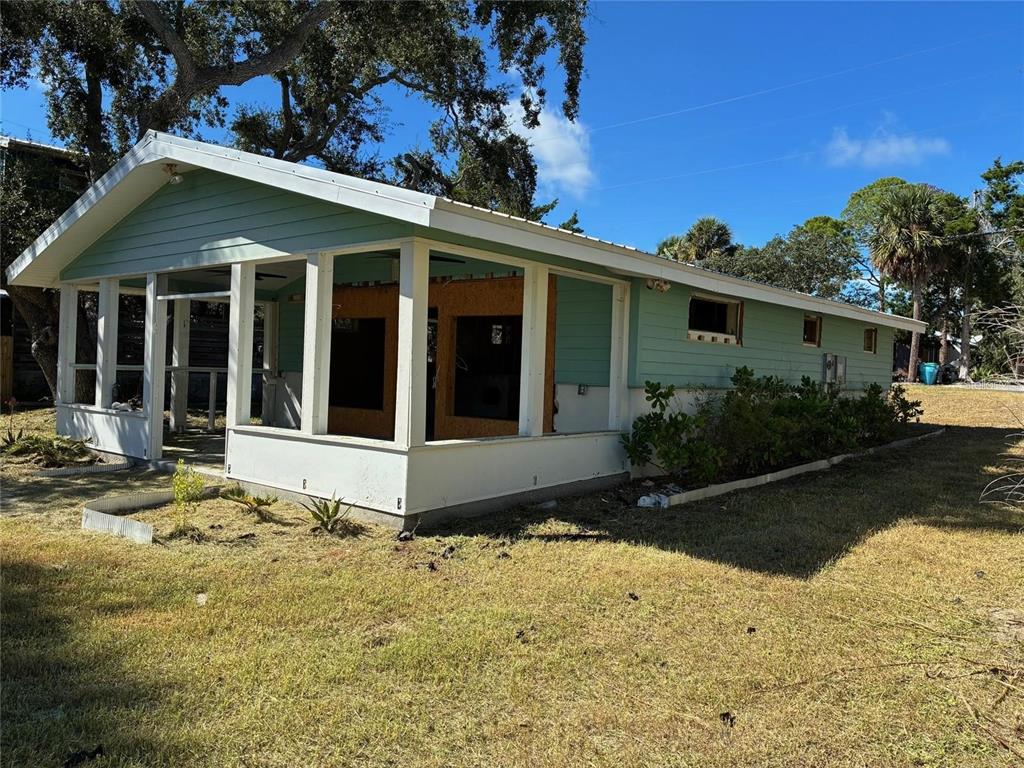 A light green house with a screened-in porch and exposed wooden wall panels — 1170 WHIDDON AVENUE, CEDAR KEY, FL