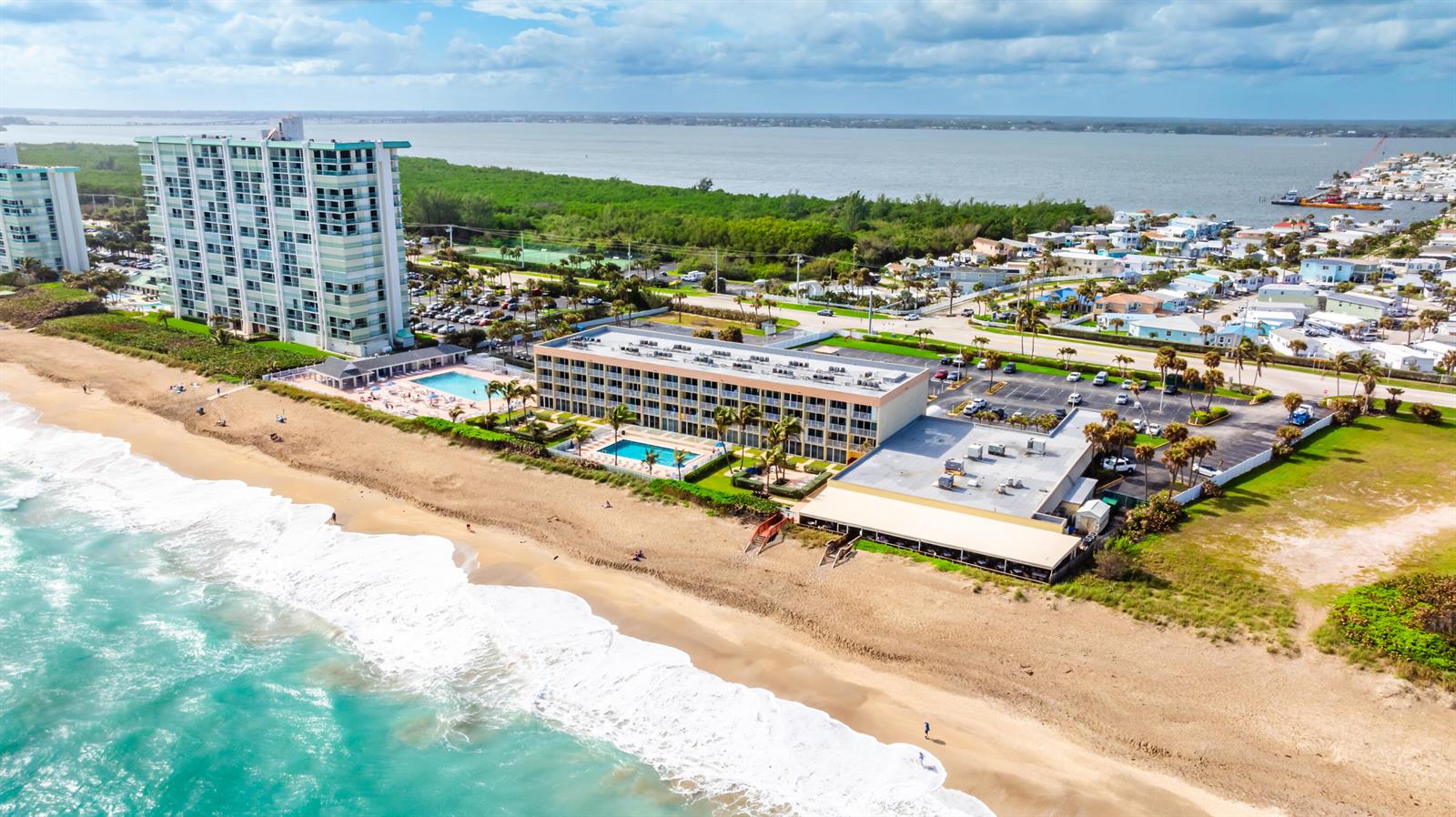 An aerial view shows a beachfront hotel with two pools, a parking lot, and ocean — 9800 S Ocean Drive # 415, Jensen Beach FL 34957, JENSEN BEACH, FL