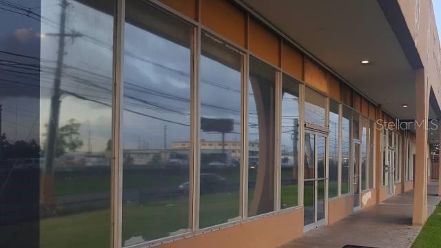 A commercial building exterior features large glass windows and a covered walkway with orange pillars — PR 190 int PONTEZUELA AVENUE, CAROLINA, PR