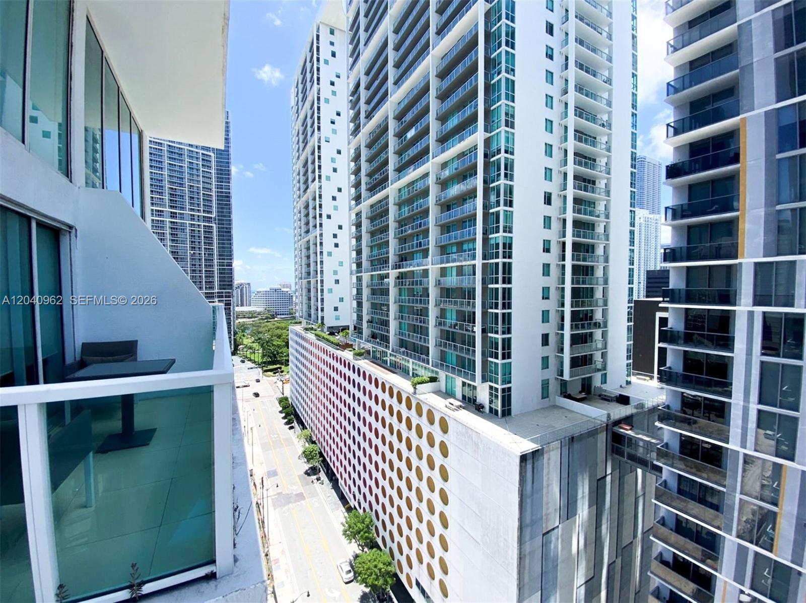 A high-angle view shows a balcony overlooking a city street and surrounding modern apartment towers — 41 SE 5th St # 1006, Miami FL 33131, MIAMI, FL