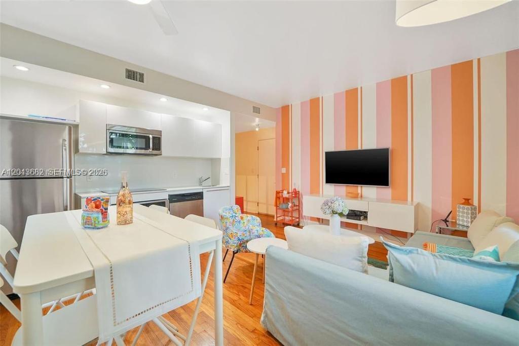A living room and kitchen area features striped wallpaper, a white dining table, and hardwood floors — 1410 Euclid Ave # 1, Miami Beach FL 33139, MIAMI BEACH, FL