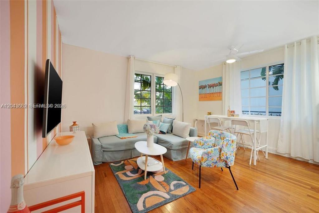 A living room features striped walls, a light blue sectional sofa, and hardwood flooring — 1410 Euclid Ave # 1, Miami Beach FL 33139, MIAMI BEACH, FL