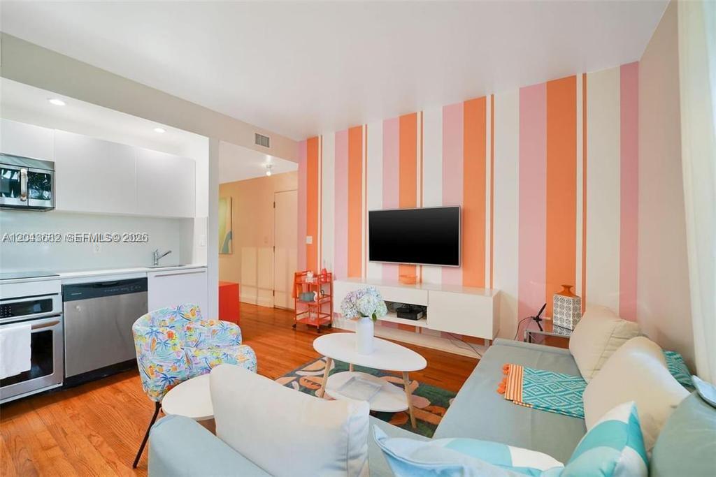 A living room with a striped accent wall, a television, and an adjacent kitchen area — 1410 Euclid Ave # 1, Miami Beach FL 33139, MIAMI BEACH, FL