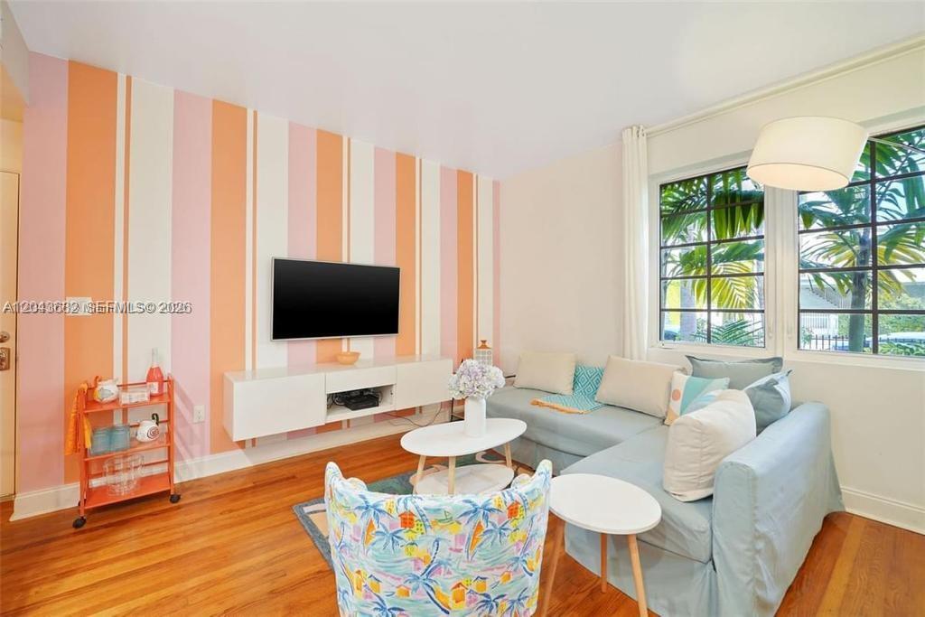 A living room features striped walls, a wall-mounted television, a sectional sofa, and hardwood floors — 1410 Euclid Ave # 1, Miami Beach FL 33139, MIAMI BEACH, FL