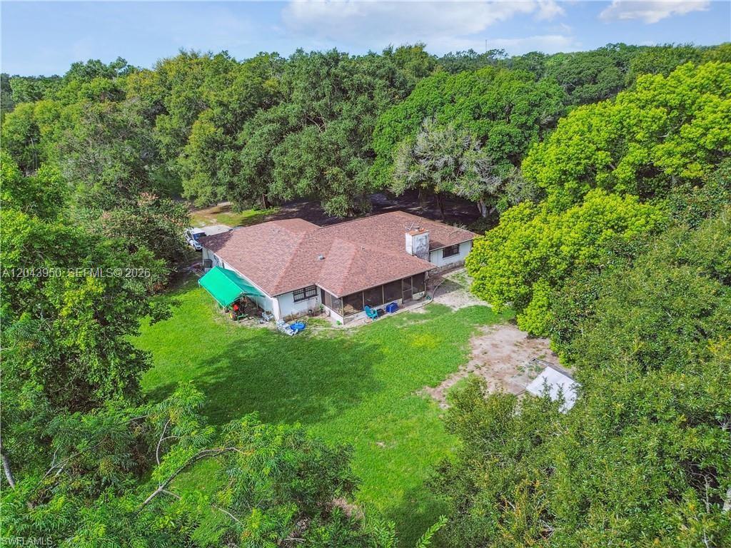 An aerial view shows a single-story house with a brown roof surrounded by dense trees — OTHER CITY - IN THE STATE OF FLORIDA, MS