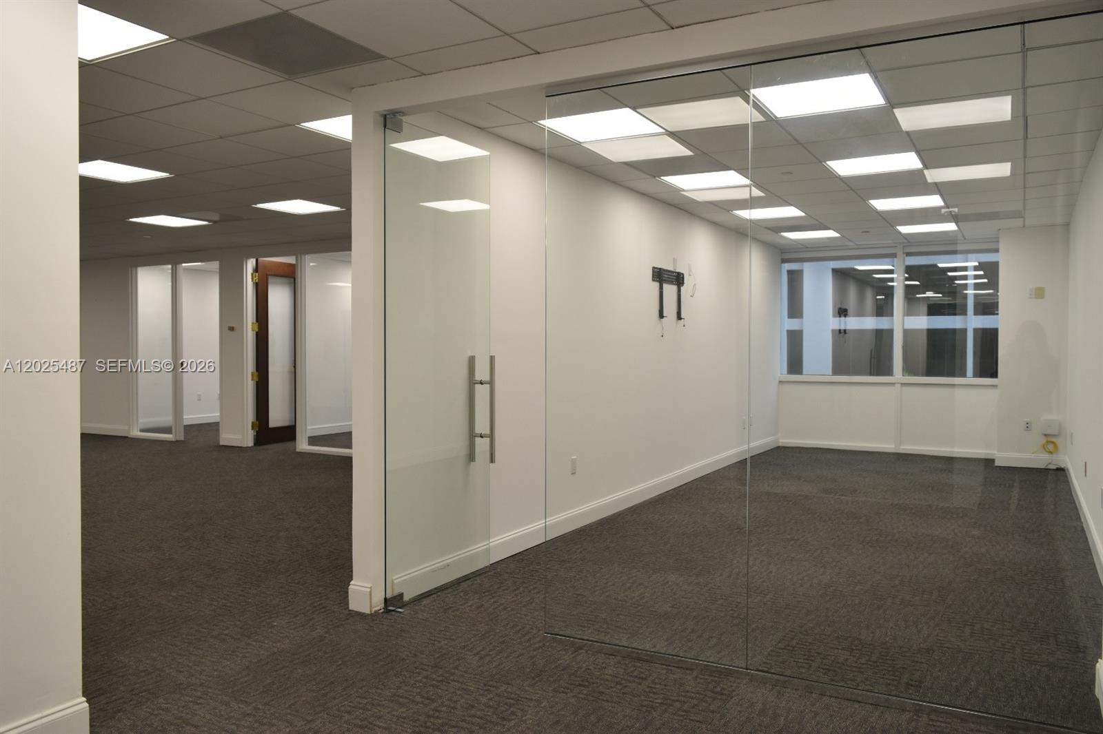 An empty office space features glass partitions, gray carpeting, and a drop ceiling with lights — 1200 Brickell Ave # 425, Miami FL 33131, MIAMI, FL