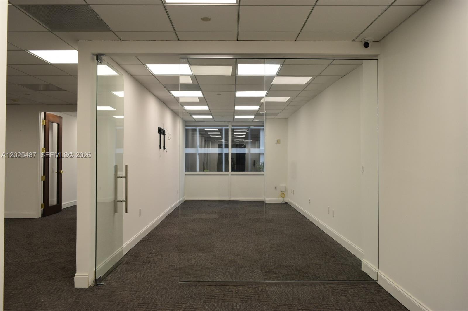 An empty office space features glass walls, a drop ceiling, and dark carpet flooring — 1200 Brickell Ave # 425, Miami FL 33131, MIAMI, FL