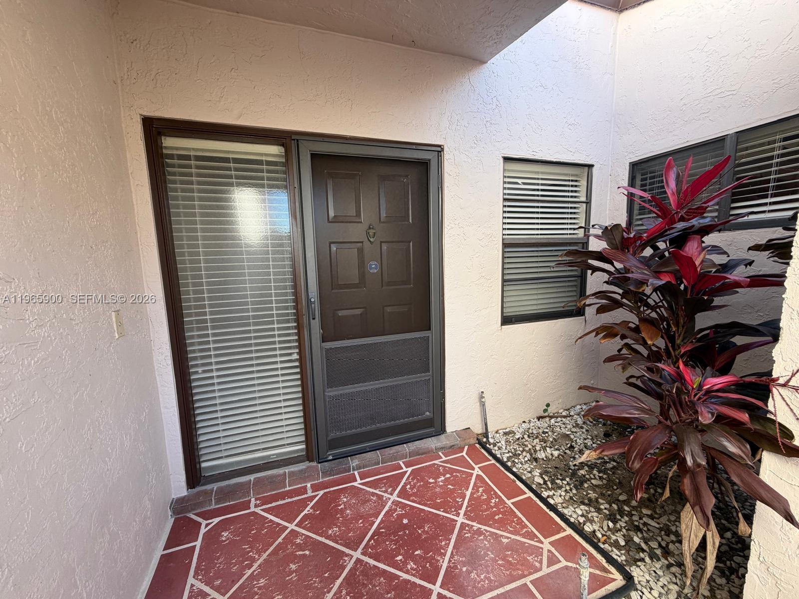 A front entryway features a brown door with a screen, a side window, and tiled flooring — 6180 Kings Gate Cir, Delray Beach FL 33484, DELRAY BEACH, FL