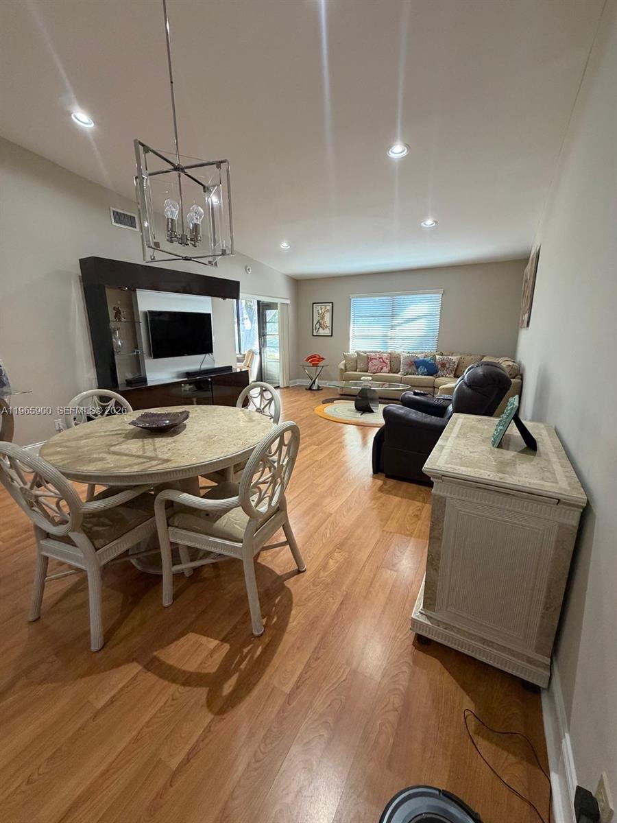 A living and dining area features light wood flooring, a round table, and neutral furniture — 6180 Kings Gate Cir, Delray Beach FL 33484, DELRAY BEACH, FL