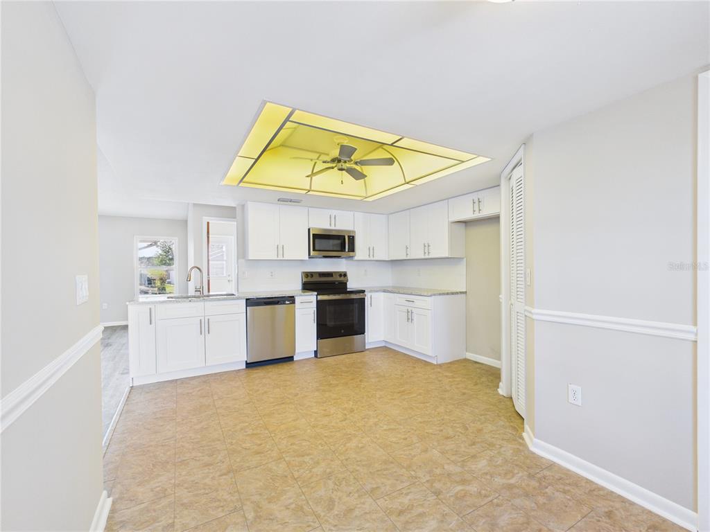 A kitchen with white cabinets, stainless steel appliances, and a large recessed ceiling light fixture — 10482 S CLINT LOOP, FLORAL CITY, FL