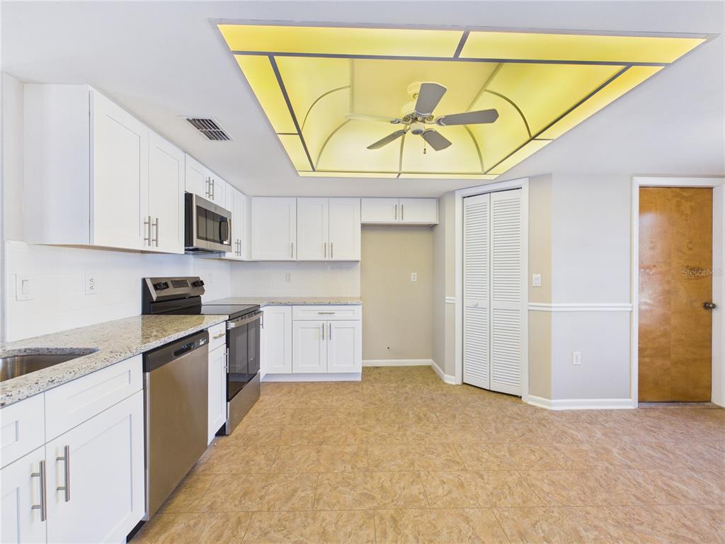 A kitchen features white cabinets, granite countertops, stainless steel appliances, and a large recessed ceiling light — 10482 S CLINT LOOP, FLORAL CITY, FL