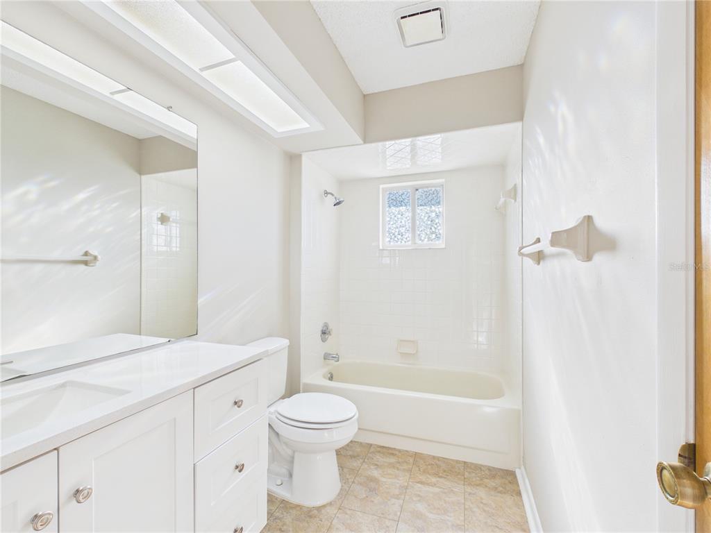 A bathroom features a white vanity, a toilet, and a shower-tub combination with white tile — 10482 S CLINT LOOP, FLORAL CITY, FL