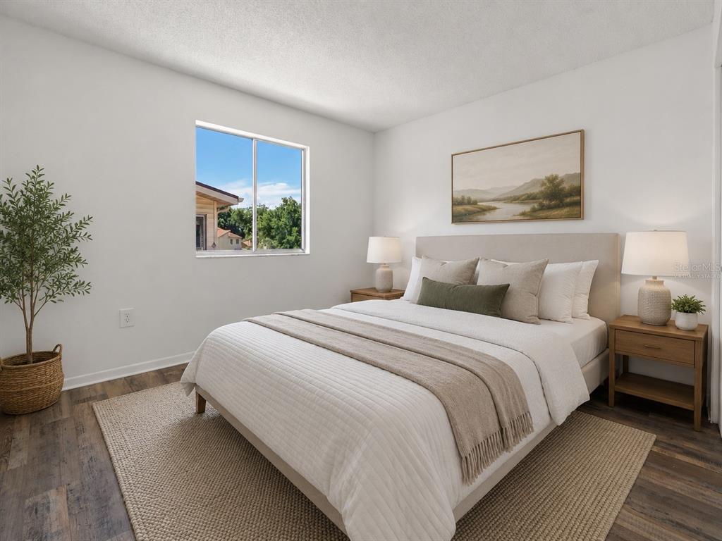 A bedroom features a bed with neutral bedding, two nightstands, a potted plant, and a window — 1016 SPRING MEADOW DRIVE UNIT 12, KISSIMMEE, FL
