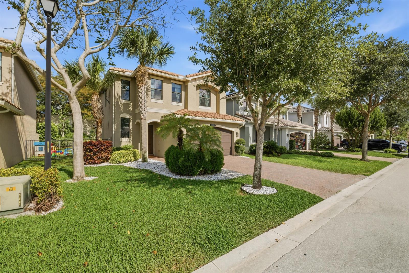 A two-story suburban house with a brick driveway, palm trees, and a manicured front lawn — 13769 Moss Agate Avenue, Delray Beach FL 33446, DELRAY BEACH, FL