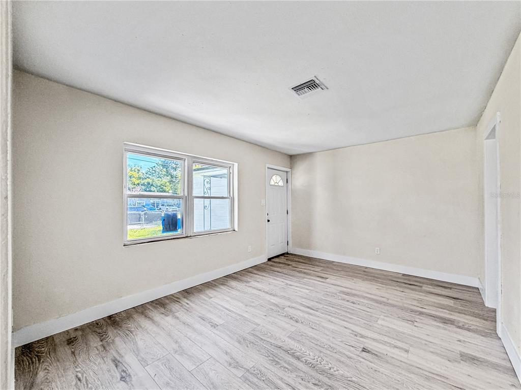 An empty room with light-colored walls, wood-look flooring, a window, and a white door — 642 20TH STREET, ORLANDO, FL