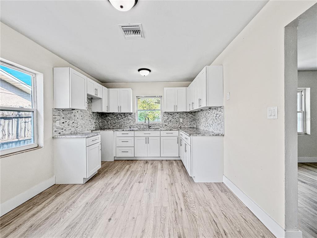 A kitchen with white cabinets, granite countertops, a mosaic tile backsplash, and light wood flooring — 642 20TH STREET, ORLANDO, FL