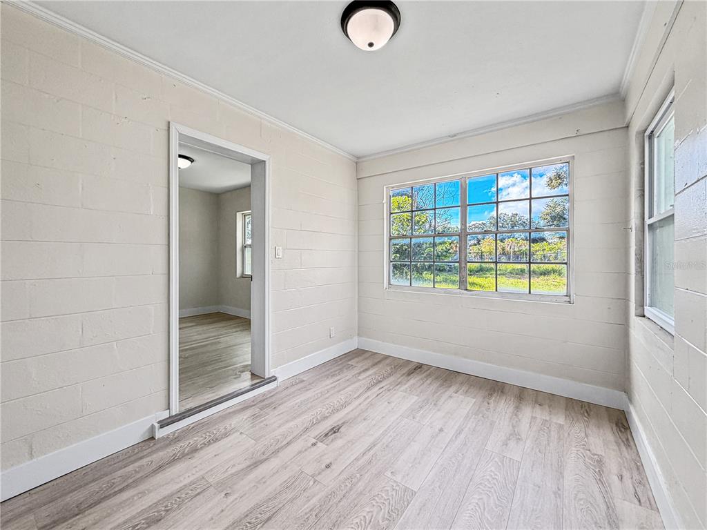 A room with light-colored block walls, wood-look flooring, and a large window overlooking greenery — 642 20TH STREET, ORLANDO, FL