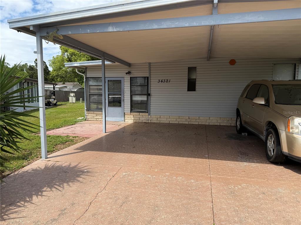 A carport with a concrete floor is attached to the side of a residential home — 34321 COUNTRYSIDE DRIVE, WESLEY CHAPEL, FL