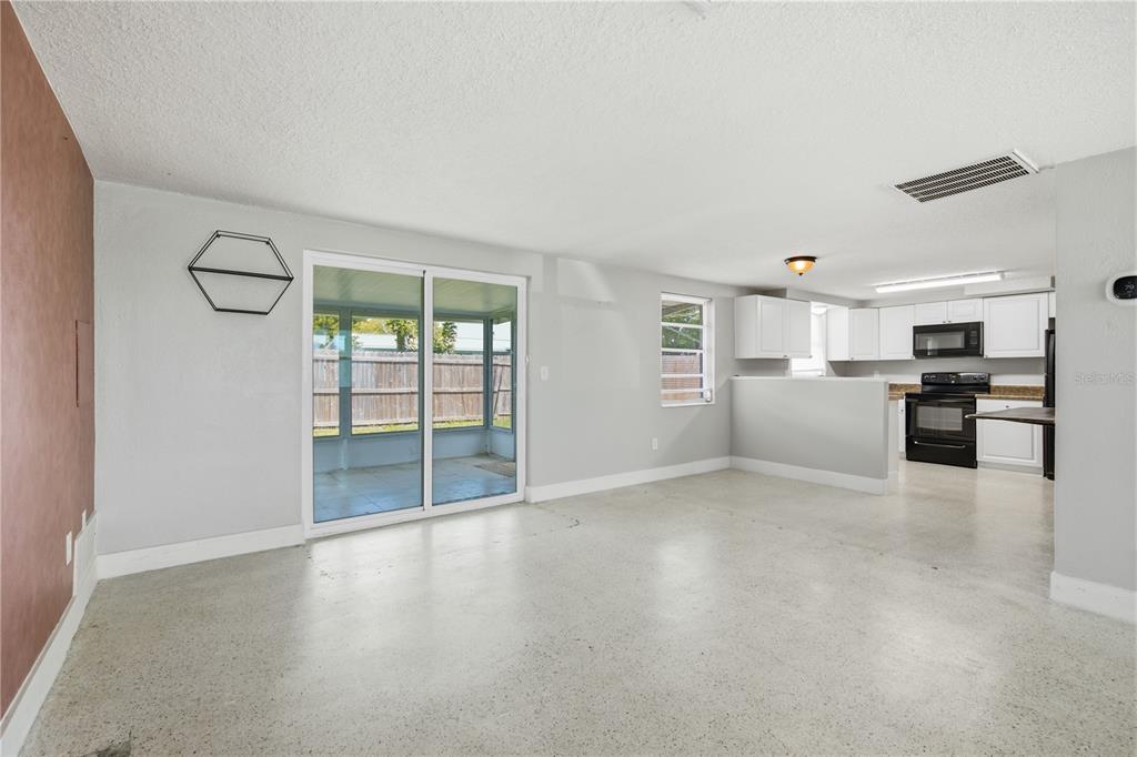 A living room with light gray walls, concrete floors, and a view into the kitchen — 2051 PEGGY DRIVE, HOLIDAY, FL