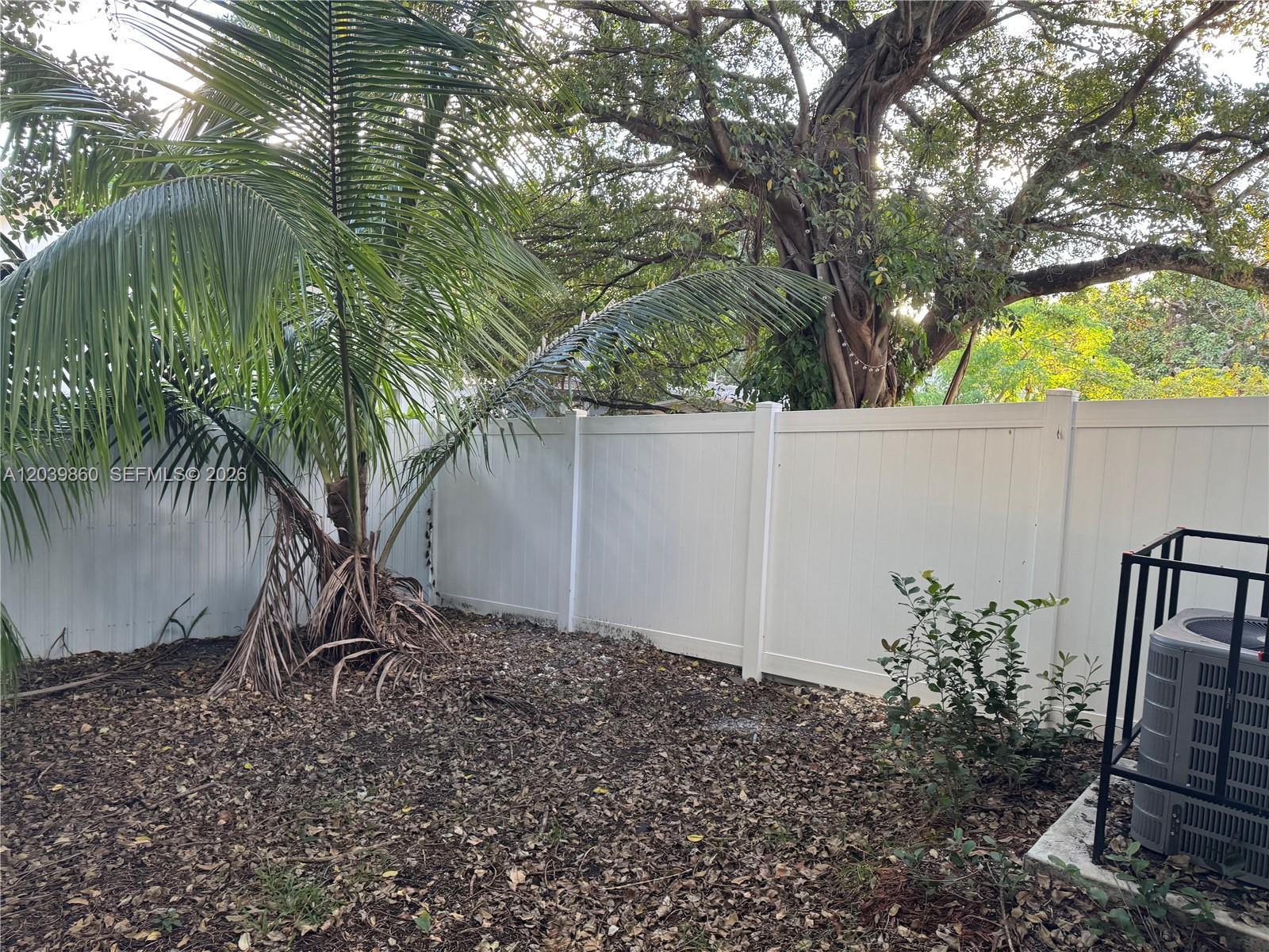A backyard features a palm tree, a white vinyl fence, and an air conditioning unit — 2730 NW 44th Steet # 3, Miami FL 33142, MIAMI, FL