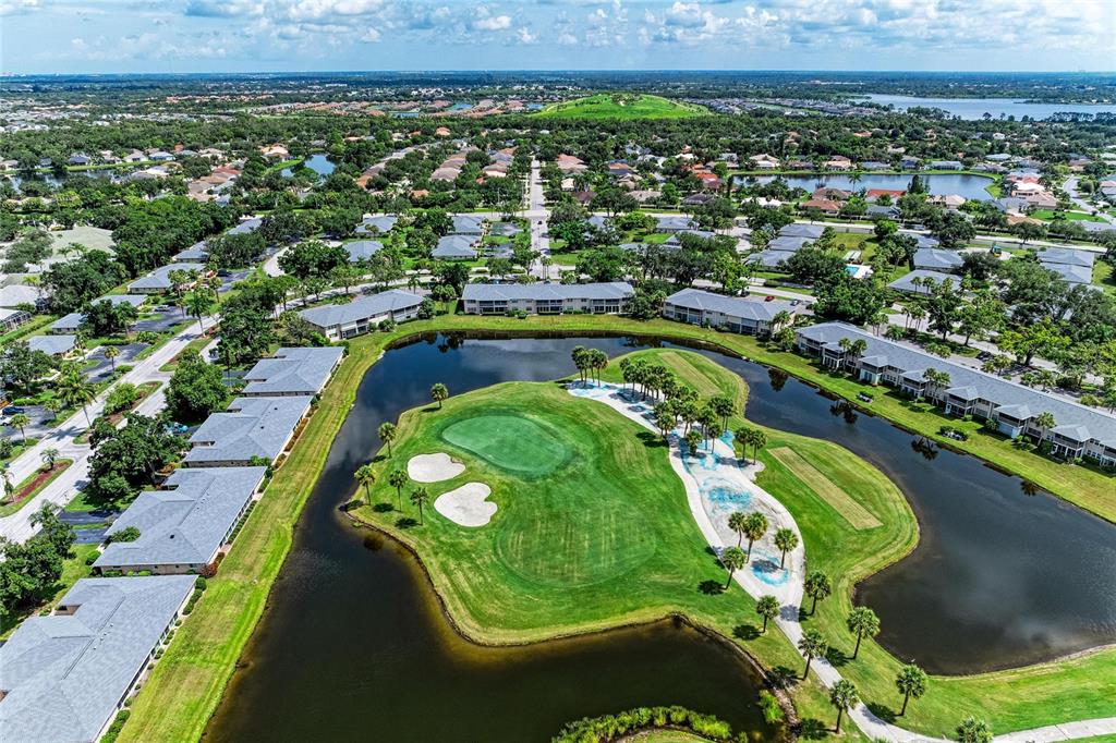 An aerial view shows a golf course green surrounded by a pond and residential buildings — 6999 W COUNTRY CLUB DRIVE N UNIT 123, SARASOTA, FL